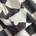 Close up of sleeve and button on a Black and White chess pattern long sleeved shirt