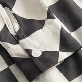 Close up of sleeve and button on a Black and White chess pattern long sleeved shirt