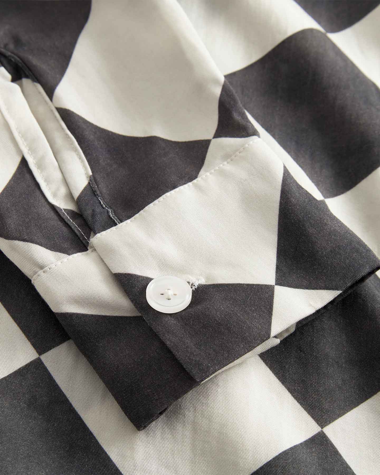 Close up of sleeve and button on a Black and White chess pattern long sleeved shirt