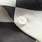 Close up of pearl button on a Black and White chess pattern long sleeved shirt