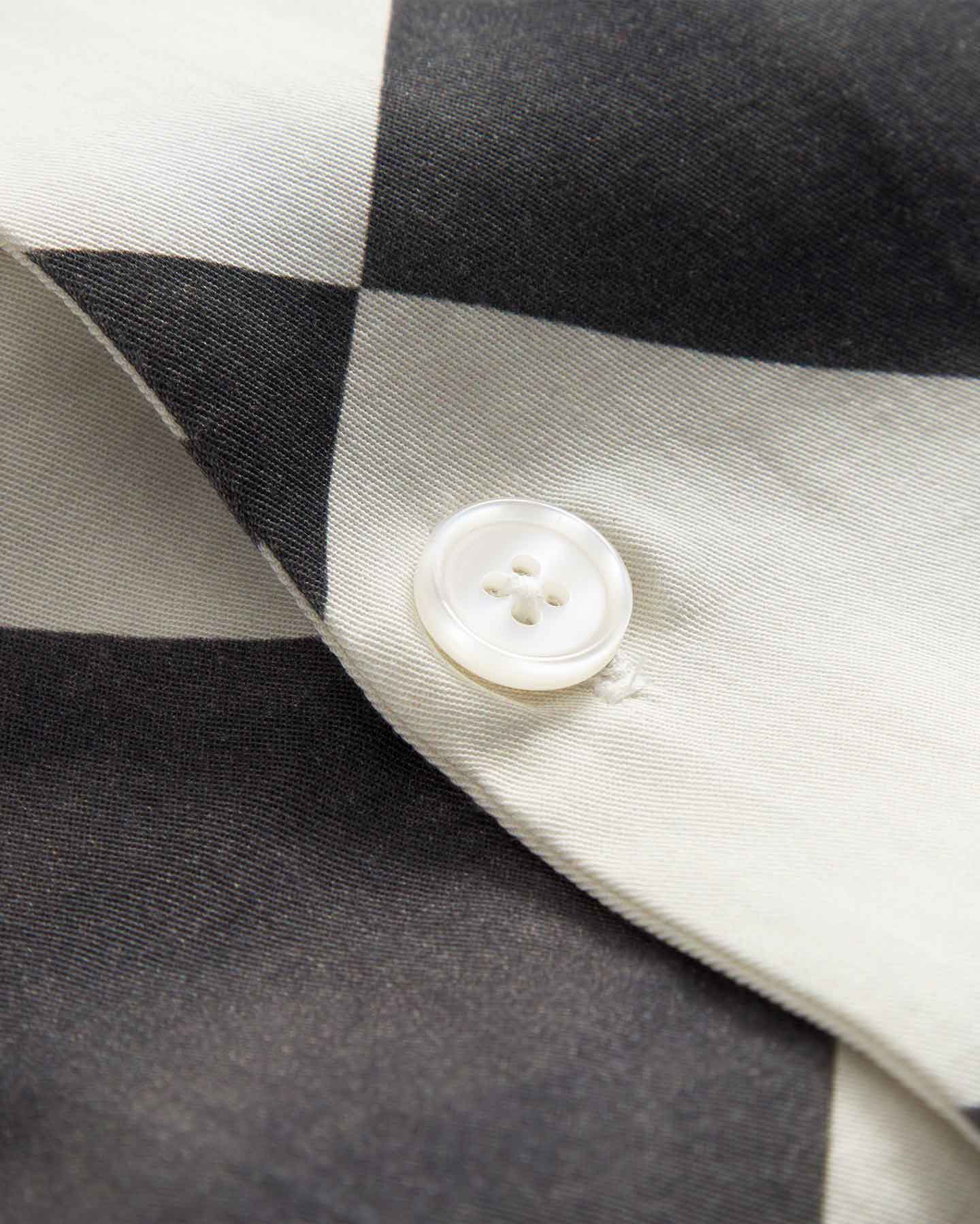 Close up of pearl button on a Black and White chess pattern long sleeved shirt
