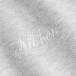 Close up of Nikben script logo embroidery on a grey hoodie