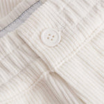 Close up of button closure on white and green corduroy track suit pants with NB embroidery