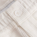 Close up of button closure on white and green corduroy track suit pants with NB embroidery