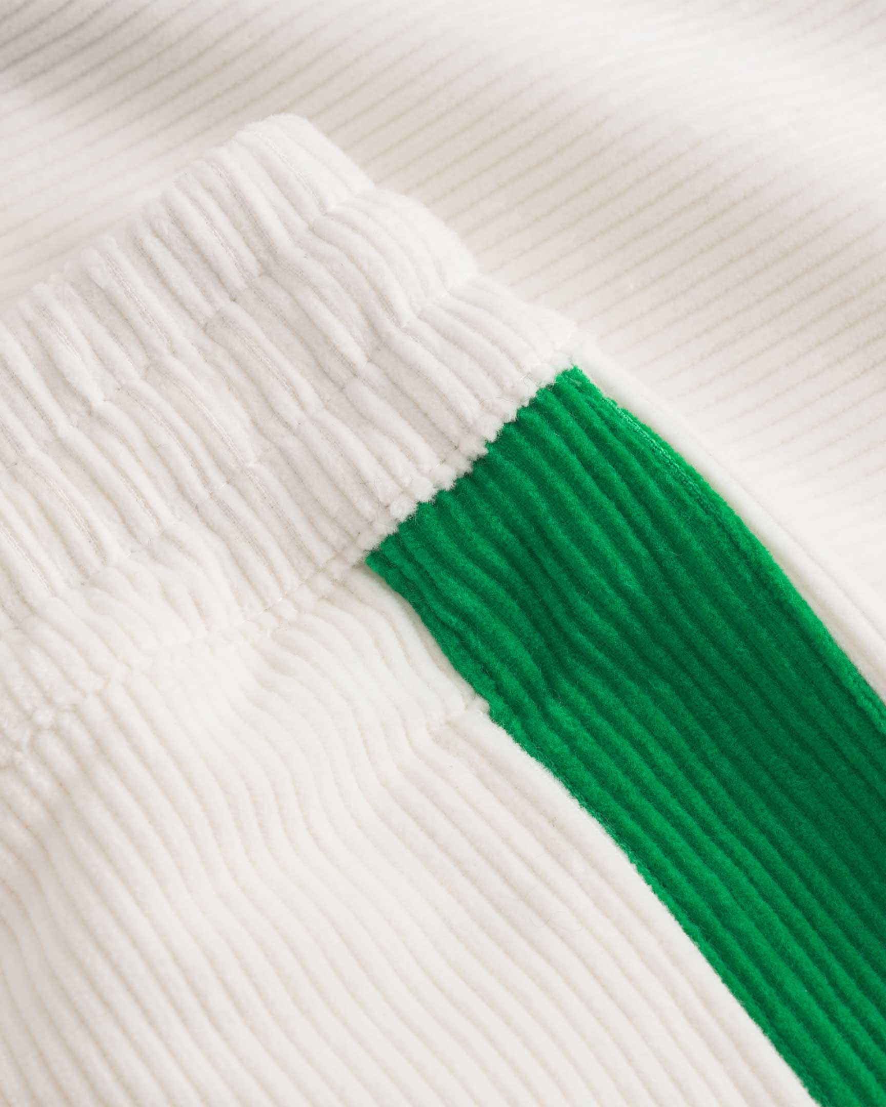 Close up of white and green corduroy track suit pants with NB embroidery