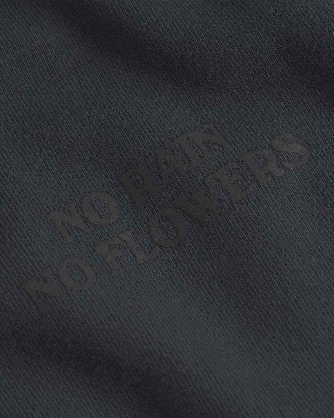 Close up of "no rain no flowers" print on a black cropped hoodie