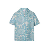 A light blue short-sleeved men's shirt with a multicolor graphic pattern, an open collar, and a button closure at the front.