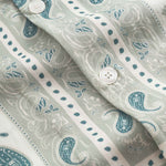 Close up on pearl buttons on a Vintage pale yellow short sleeved shirt with paisley pattern