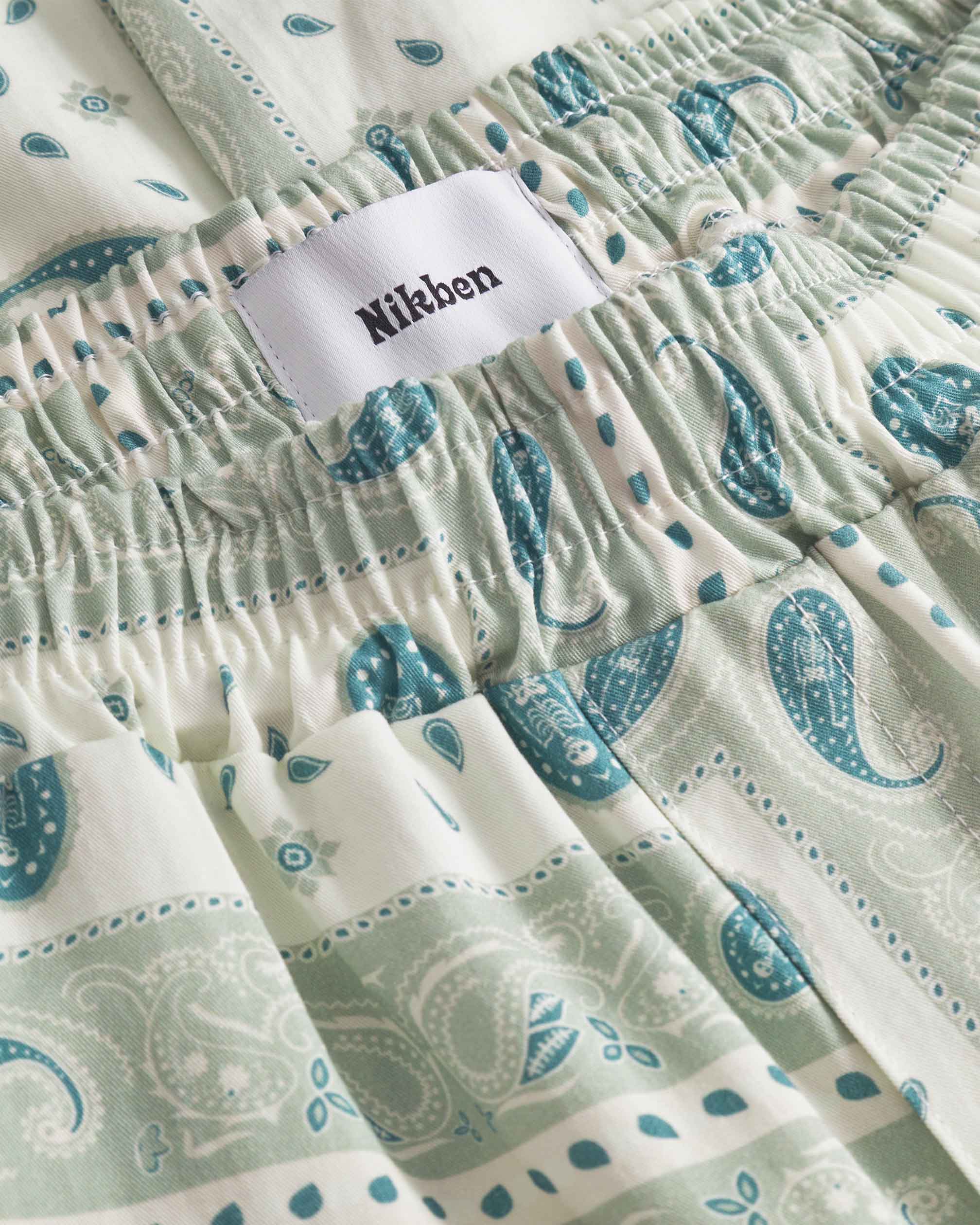 Close up of waist on a pair of vintage pale yellow paisley pattern long pants