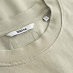 Close-up of a beige t-shirt with a brand label in the collar.