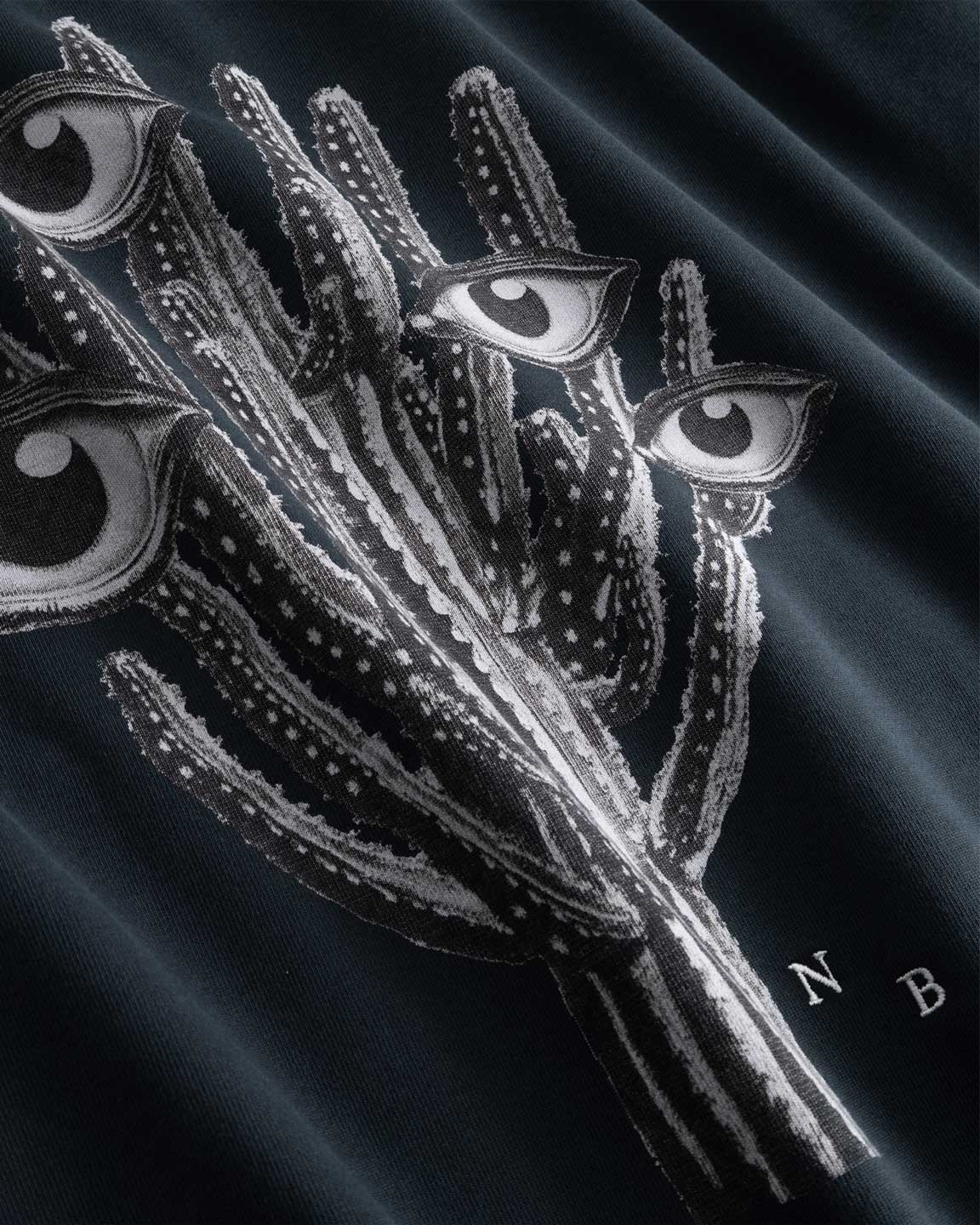 Closeup view of black and white cactus print and NB embroidered initials on black hoodie