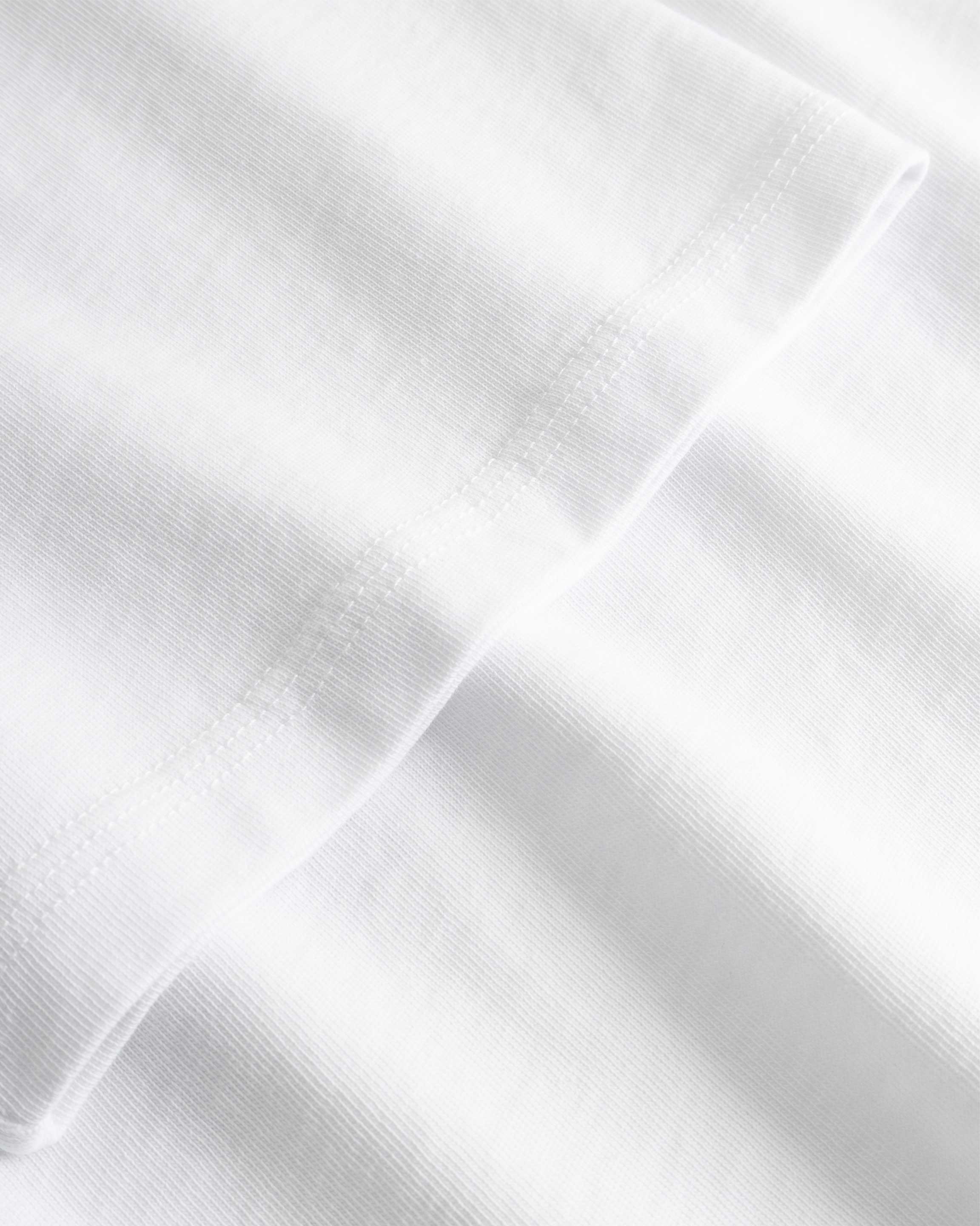 Closeup view of arm stitchings on white T-shirt