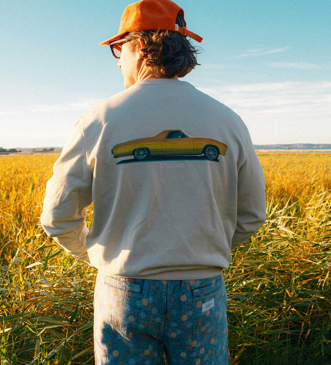 Model  wearing a beige sweatshirt with a vintage car design