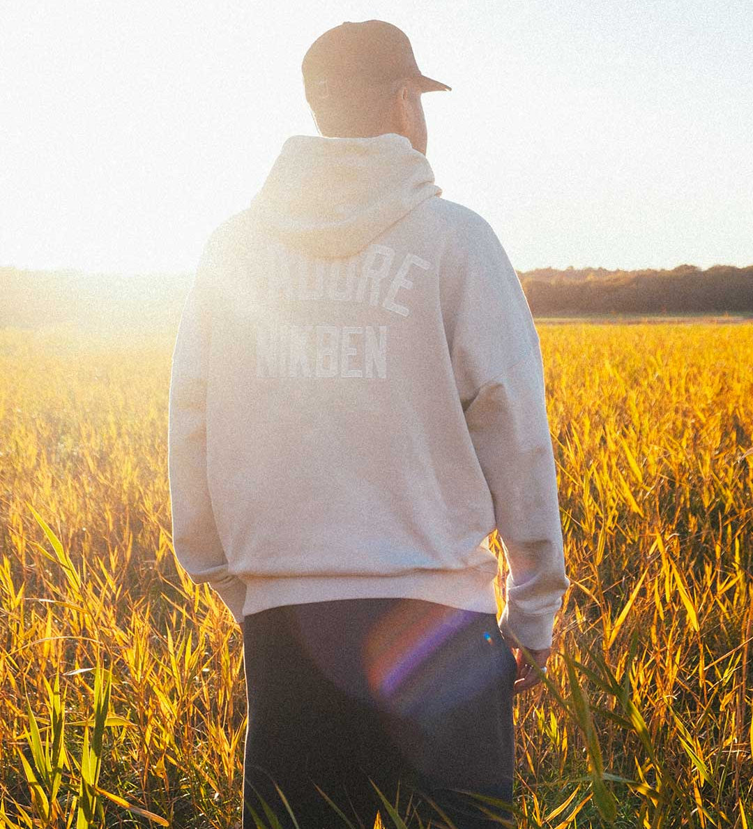 Model wearing beige hoody, with printed logo on the back