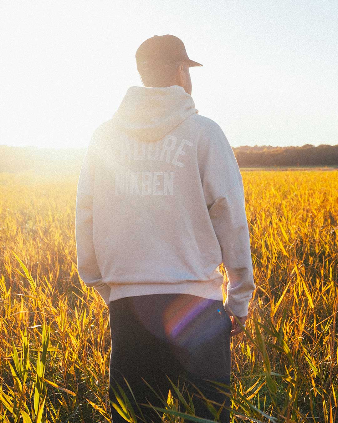 Model wearing beige hoody, with printed logo on the back