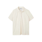 An off white, short-sleeved terry toweling shirt with pearl buttons and a collar.