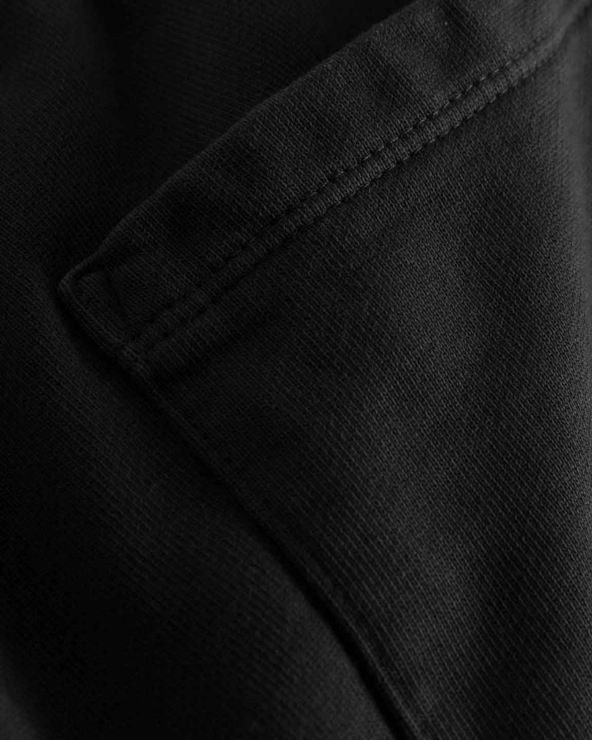 Close up of back pocket and tonal stitchings on a pair of black sweatshorts