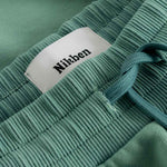 Close up of ribbed waistband and drawstrings on a pair of green sweatshorts