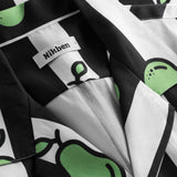 Close-up on open collar on a black and white short-sleeved vacation shirt with green pear illustrations.
