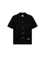 Black waffle-patterned short-sleeved shirt with two front pockets, featuring a stitched black Nikben logo on the left pocket and button closure.