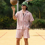 Person in a patterned outfit holding a basketball on an outdoor court