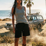 Female model wearing green ribbed tank top with white NB initials on chest