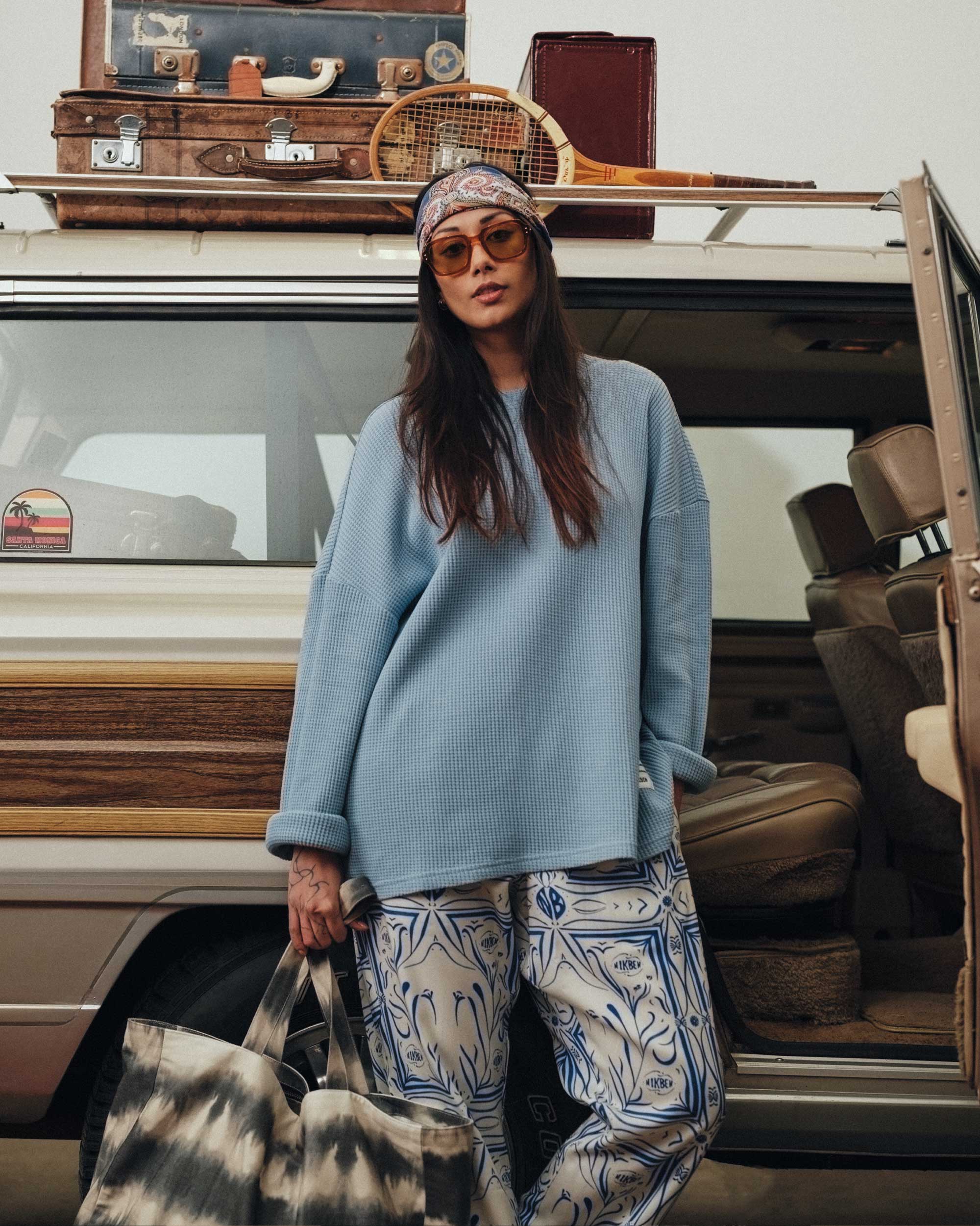 Female model wearing a sky blue waffle-patterned sweatshirt with a stitched-on material label.