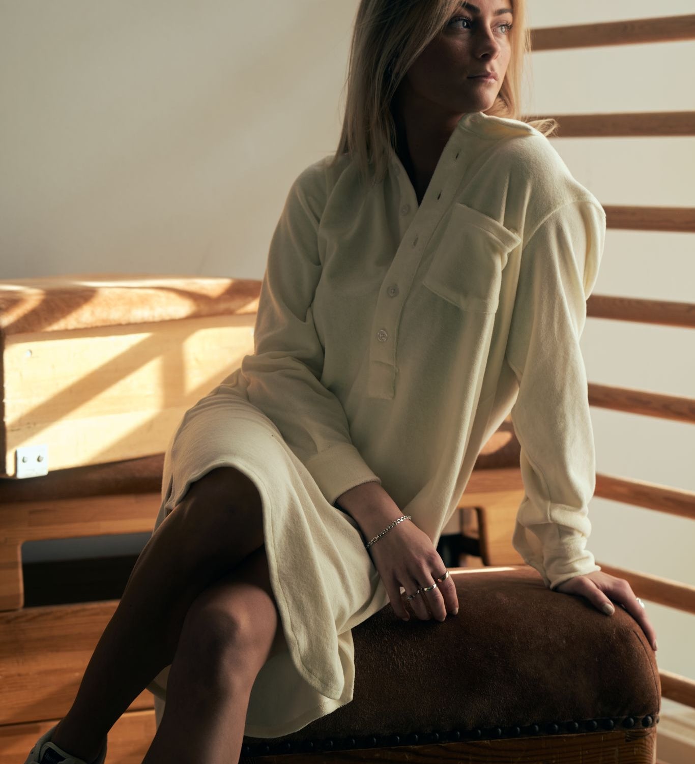 Female model wearing a white kaftan in terry toweling fabric. With half button closure and one chest pocket