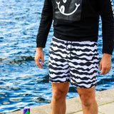 Model wearing black/white mid length swim trunks
