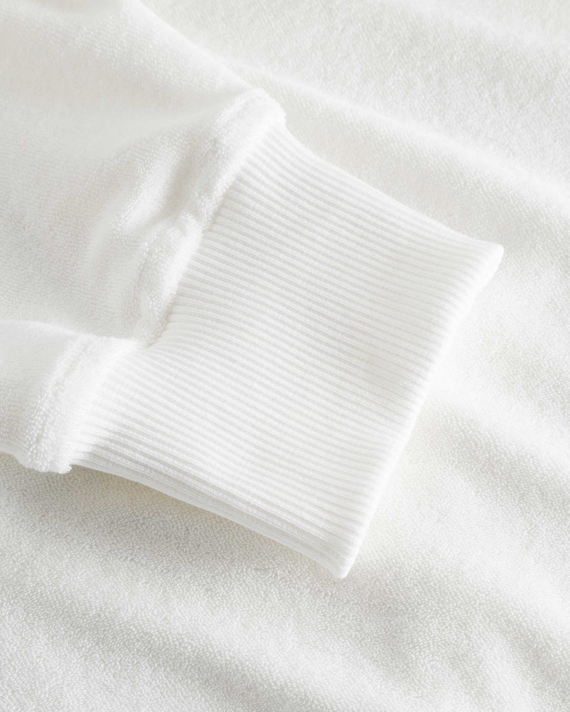 Close-up of ribbed cuffs on a white hoodie.