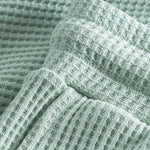 Close up of stitchings and waistband on mint green waffle-patterned mid-length shorts.