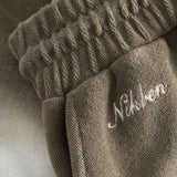 Close up on embroidered logo on brown and white low cut shorts in terry toweling fabric