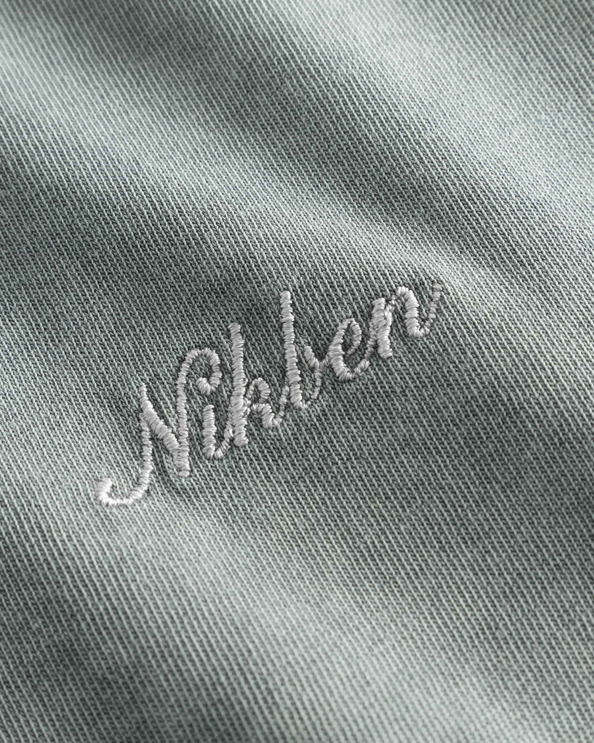 Close up of white script logo on grey t-shirt.