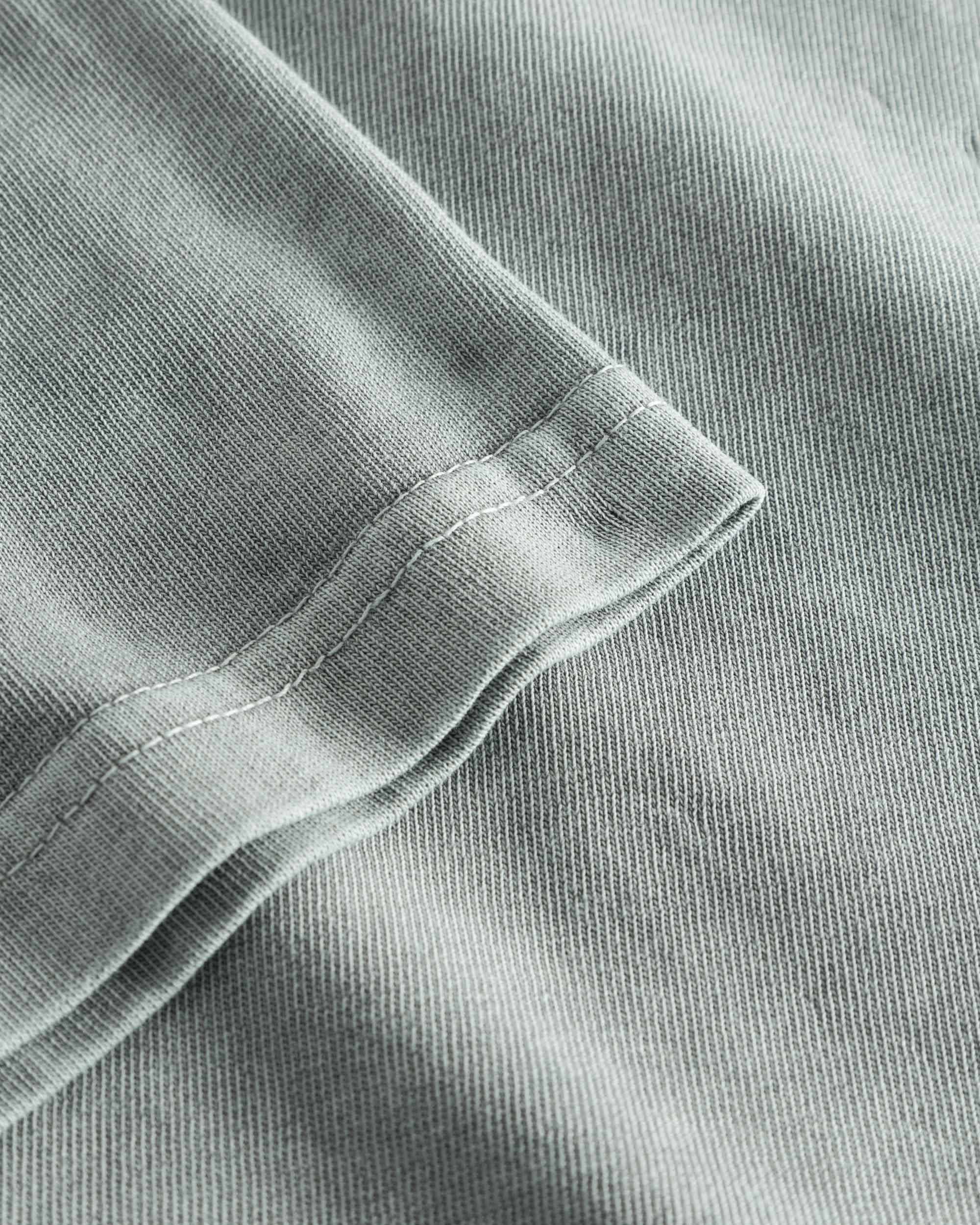 Close-up view of the sleeve and stitchings on a grey t-shirt