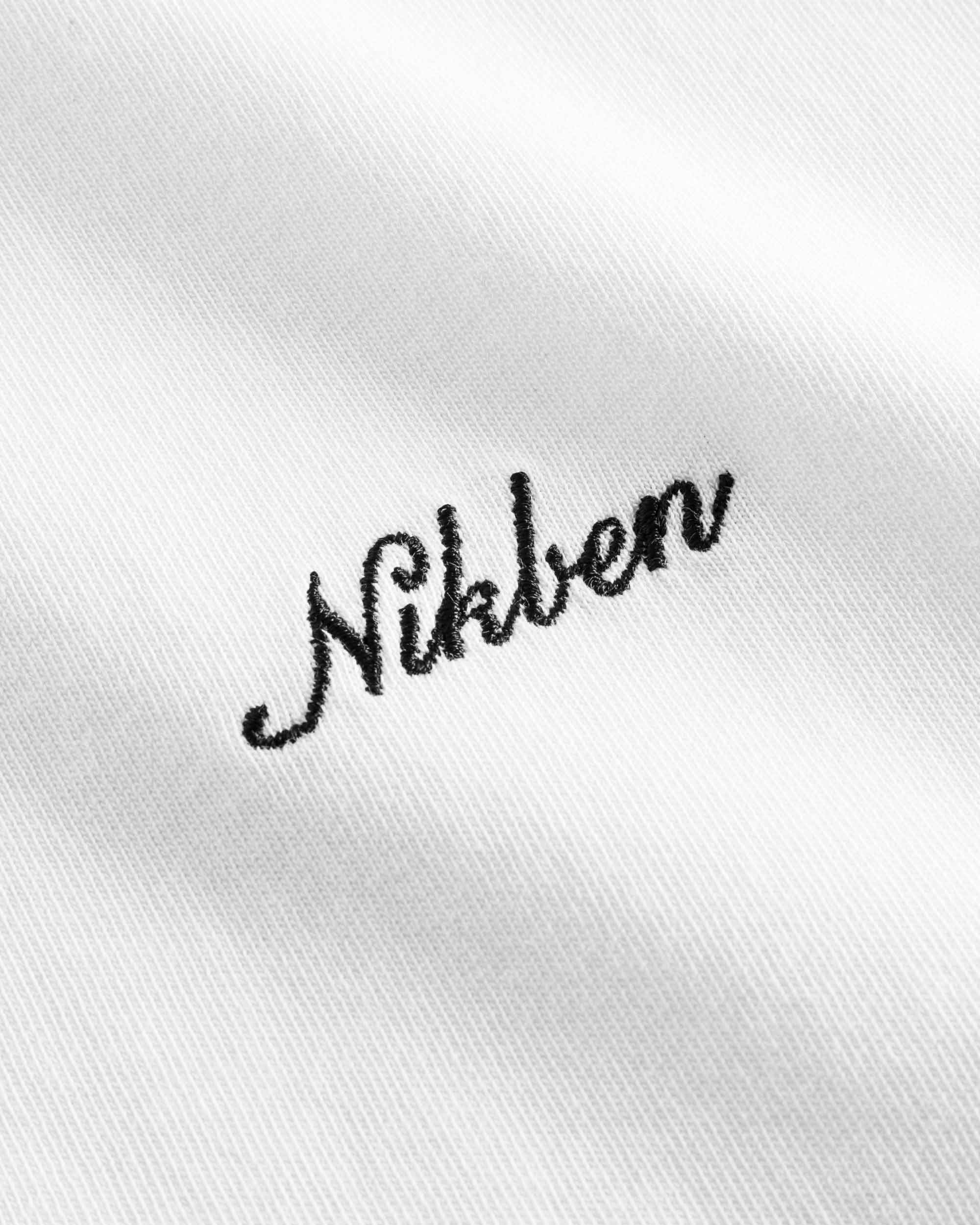 Close up of black logo script on white t-shirt.