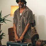 Male model wearing a dark grey short sleeve shirt with white button closure and one chest pocket