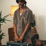 Male model wearing a dark grey short sleeve shirt with white button closure and one chest pocket