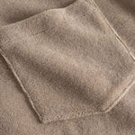 Close up on chest pocket on a light brown, short sleeve, cropped shirt