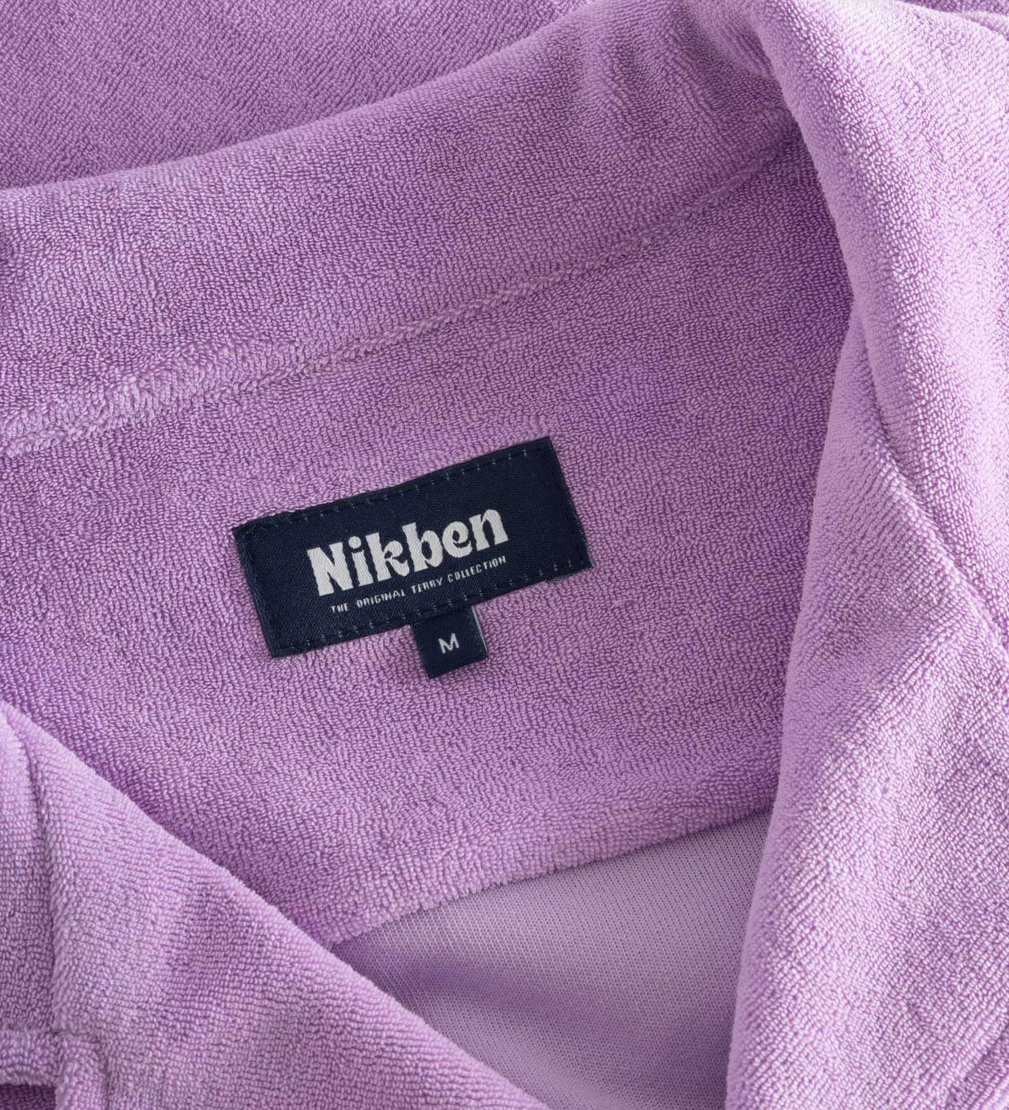 Close up on open collar and tag on a purple, short sleeve, cropped shirt