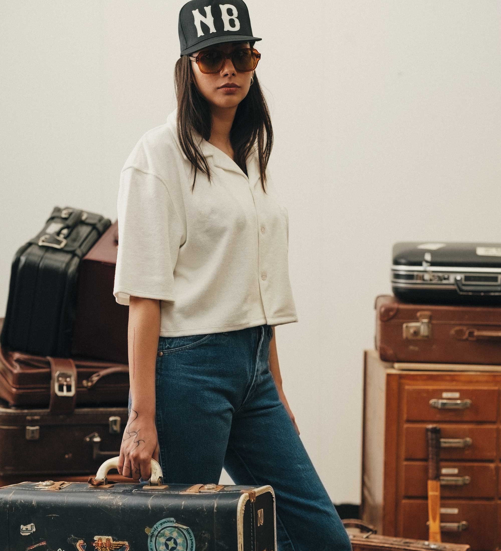Female model wearing white, short sleeve, cropped shirt with white button closure and one chest pocket
