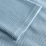 Close up on stitchings and sleeve on a sky blue waffle-patterned sweatshirt