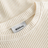 Close up on round neck on an off white waffle-patterned sweatshirt