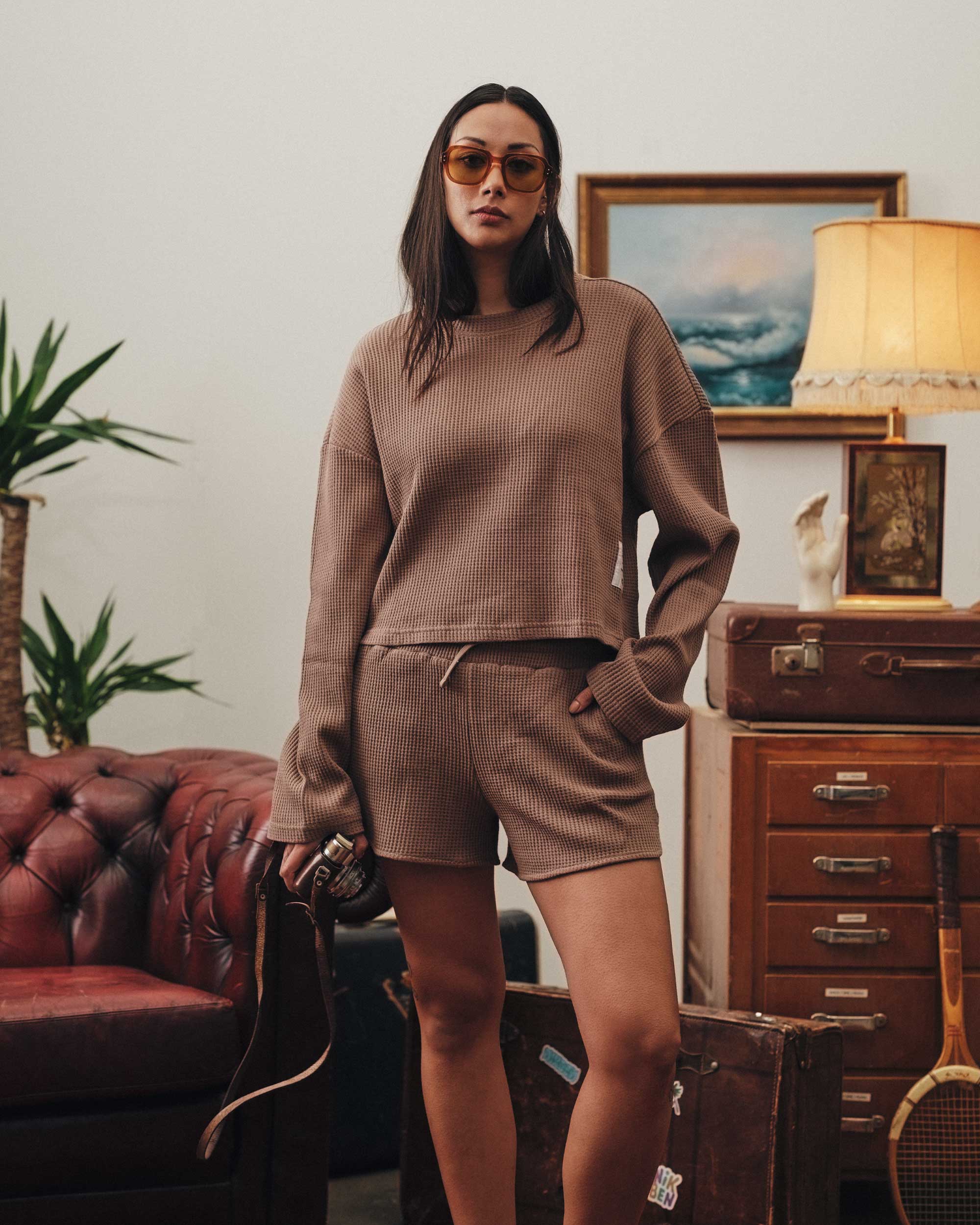 Female model wearing a brown waffle-patterned cropped sweatshirt with a stitched-on material label.