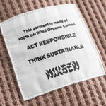 Close up on material label on a brown waffle-patterned cropped sweatshirt