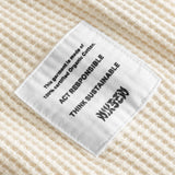 Close up on material label on an off white waffle-patterned cropped sweatshirt