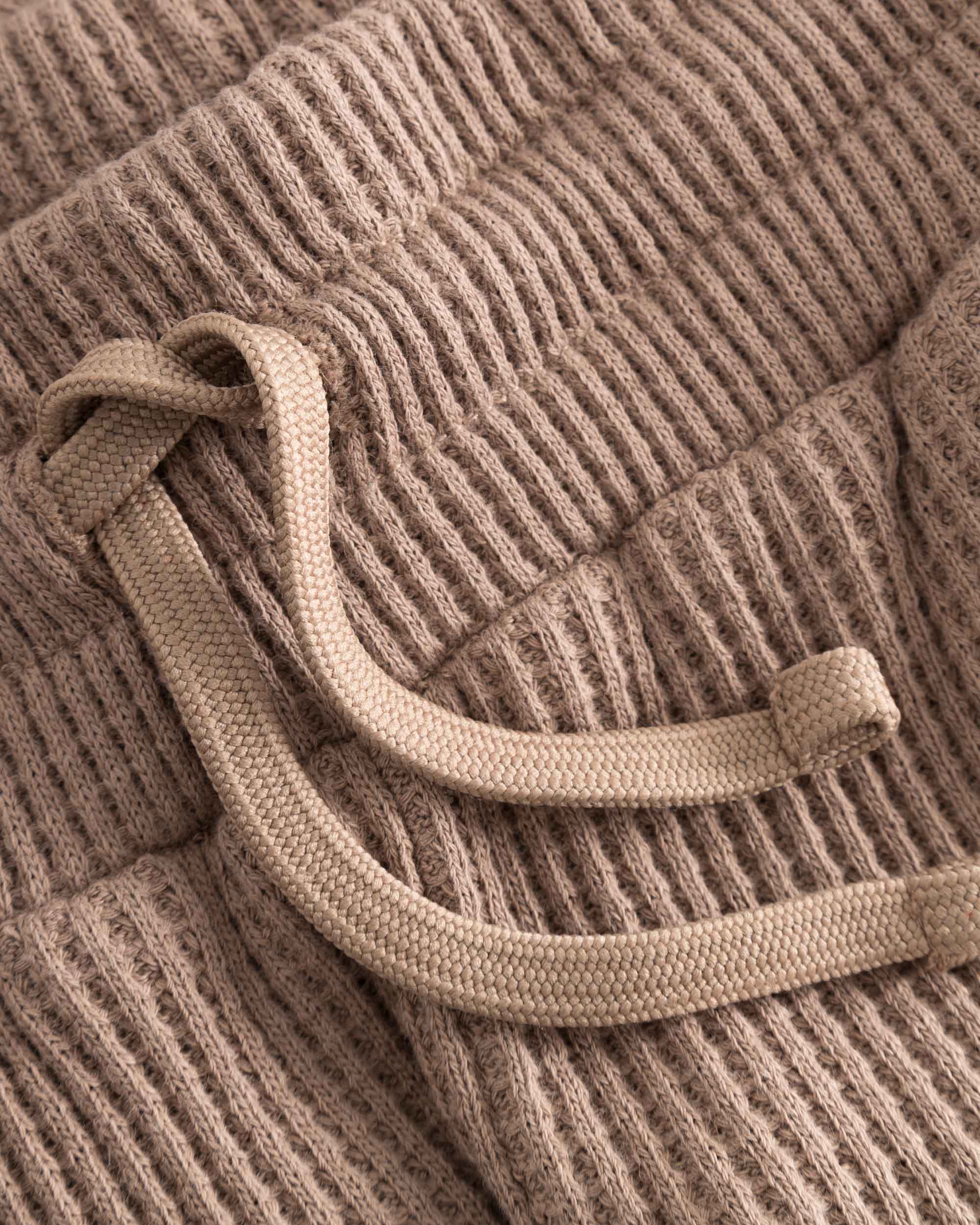 Close up of drawstring on brown waffle-patterned short-length shorts.