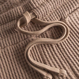Close up of drawstring on brown waffle-patterned mid-length shorts.