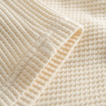 Close up of leg on off white waffle-patterned mid-length shorts.