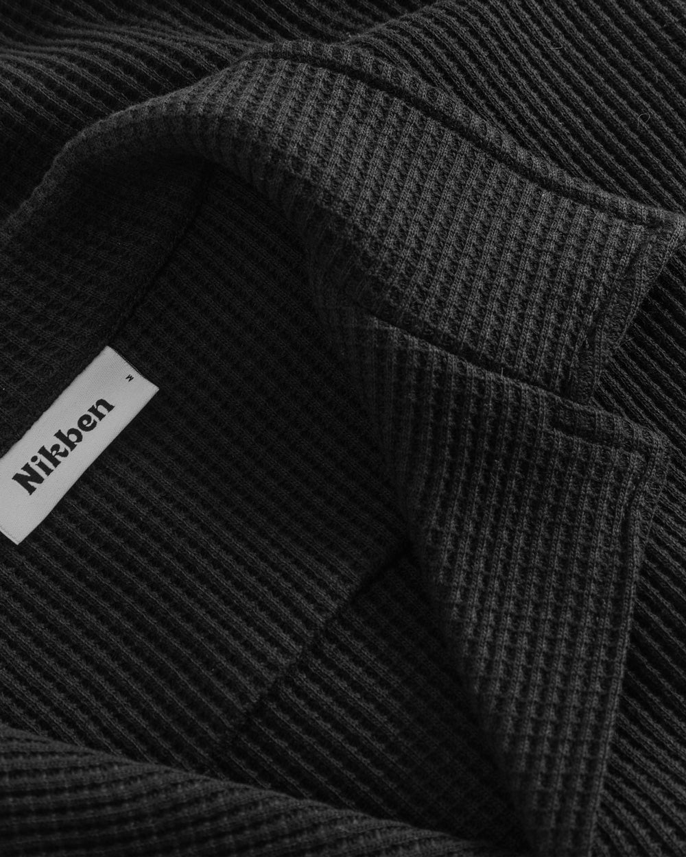 Close-up of open collar on a black waffle-patterned shirt.