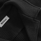Close-up of open collar on a black waffle-patterned shirt.